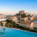 Couple sur une terrasse de villa moderne avec piscine à débordement, vue sur le château de Peñíscola, la plage et la mer.