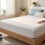 Main brossant housse de matelas anti-punaises blanche sur lit en bois clair. Chambre lumineuse pour un sommeil sain et protégé.