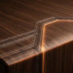 Gros plan sur une surface en bois sombre avec des coutures décoratives lumineuses incrustées le long des arêtes.